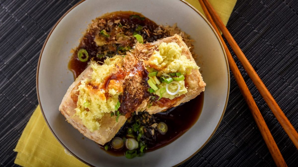 Ein Teller mit Agedashi Tofu neben einem Paar Stäbchen.