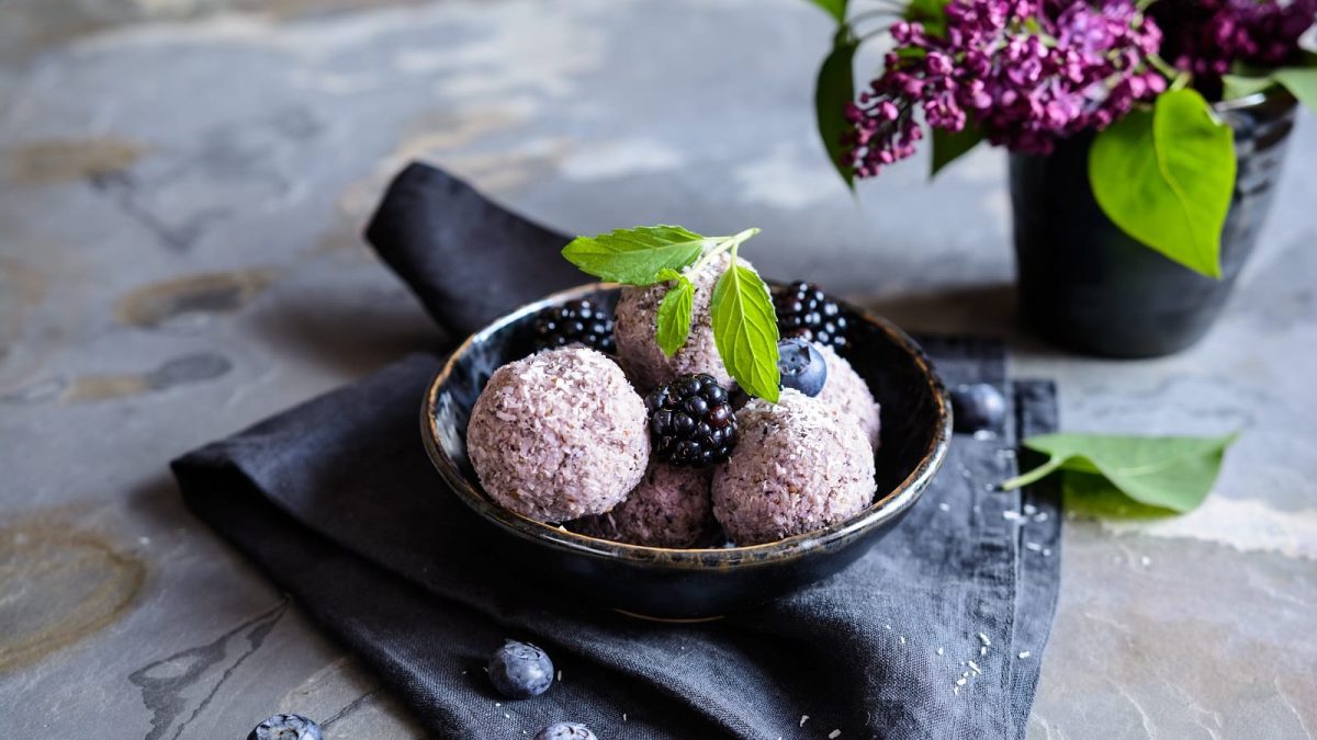 Eine schwarze Schüssel mit Chia Balls mit Brombeeren