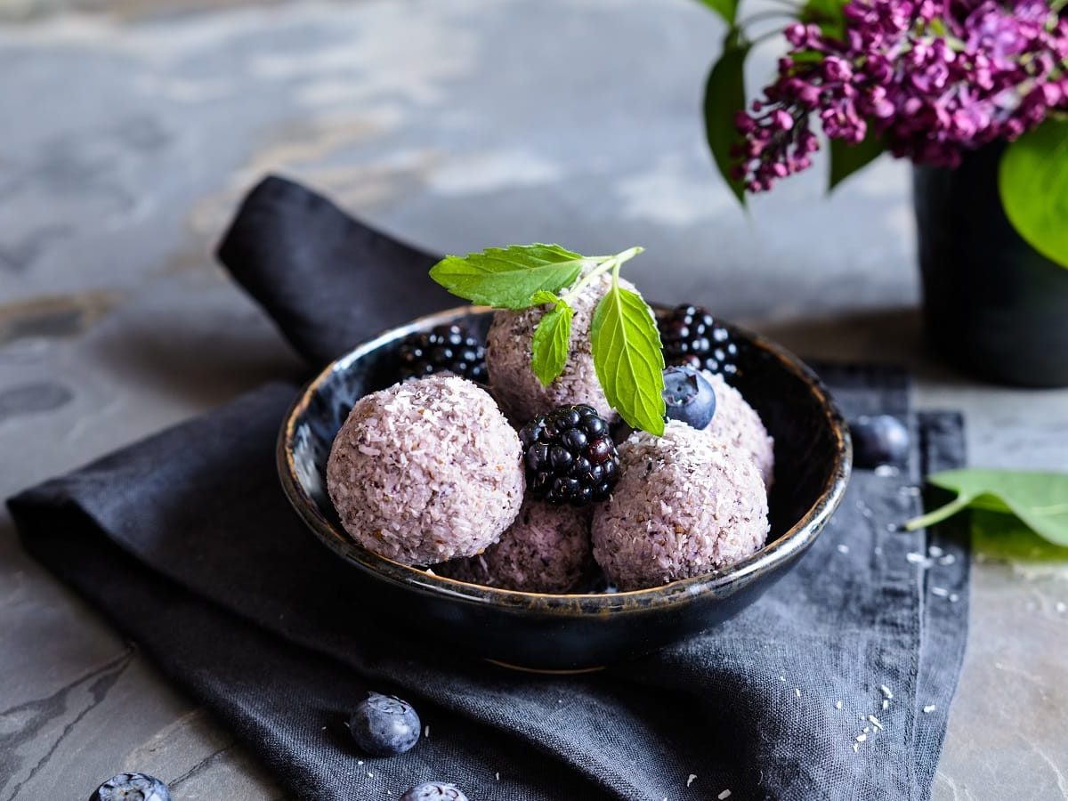 Eine schwarze Schüssel mit Chia Balls mit Brombeeren