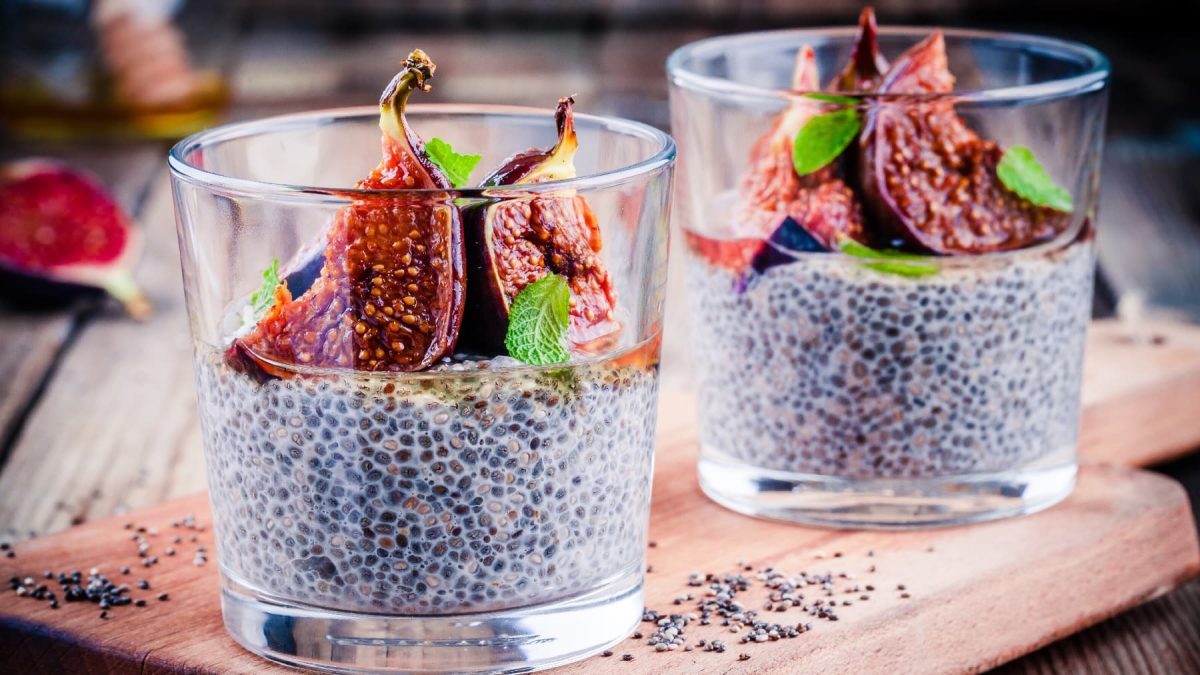 Zwei Gläser mit dem Chia-Pudding auf einem Holzbrett. Auf der Oberfläche vom Chia-Pudding sind die karamellisierten Feigen zu sehen.