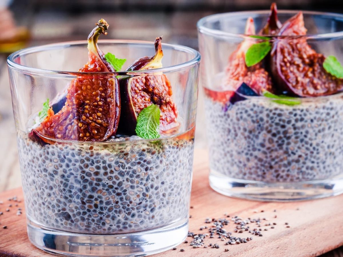 Zwei Gläser mit dem Chia-Pudding auf einem Holzbrett. Auf der Oberfläche vom Chia-Pudding sind die karamellisierten Feigen zu sehen.