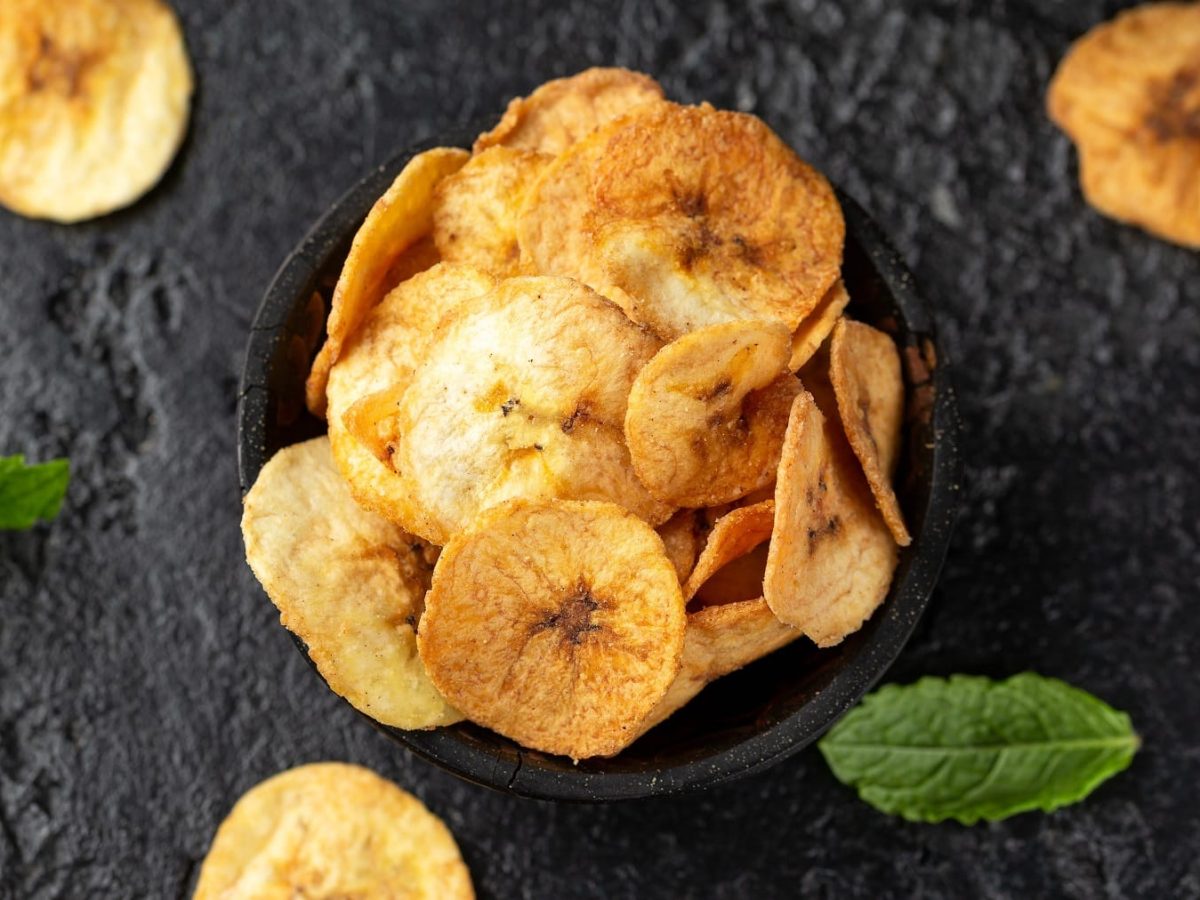 Kleine Schale voller Chicharritas garniert mit Minzblättern vor schwarzem Hintergrund.