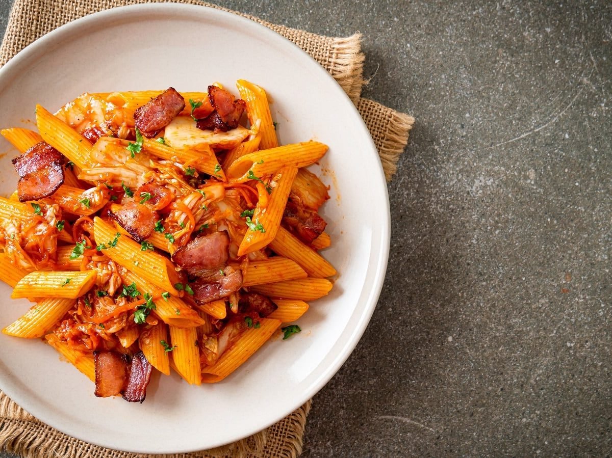 Ein weißer Teller mit Kimchi Pasta mit Bacon gefüllt.