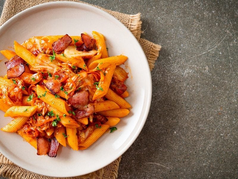 Ein weißer Teller mit Kimchi Pasta mit Bacon gefüllt.