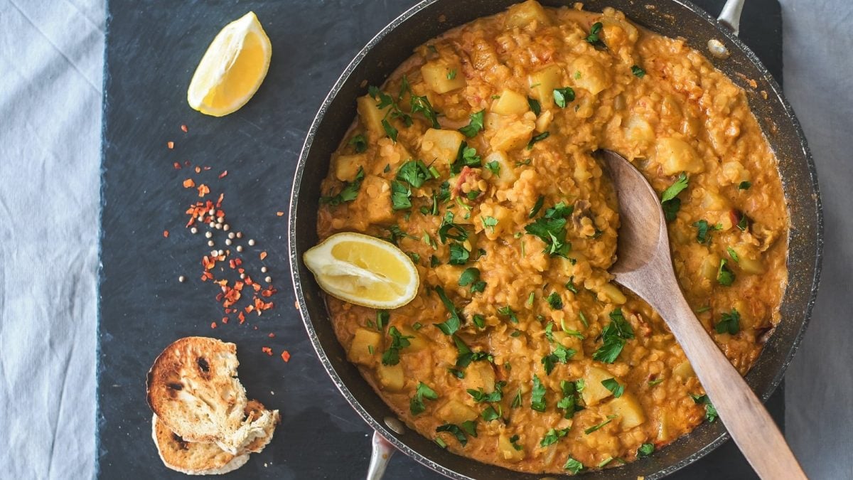 Ein Topf mit Rote-Linsen-Curry auf einer schwarzen Schieferplatte