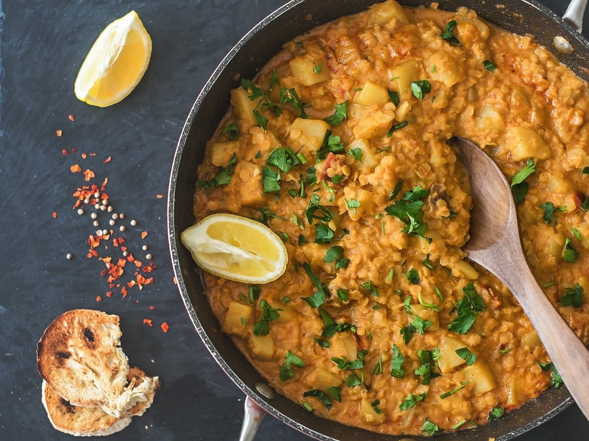 Ein Topf mit Rote-Linsen-Curry auf einer schwarzen Schieferplatte