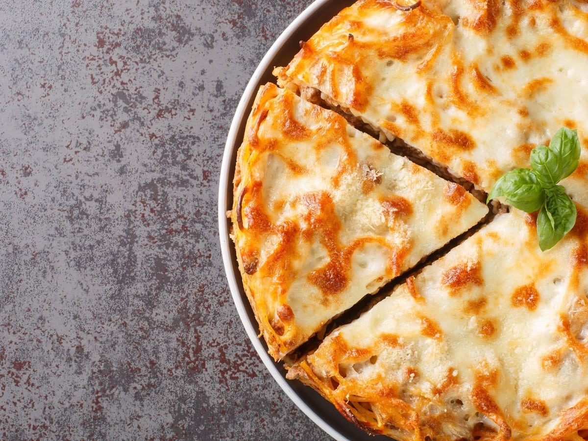 Eine runde Form mit Spaghetti-Kuchen auf grauem Hintergrund.