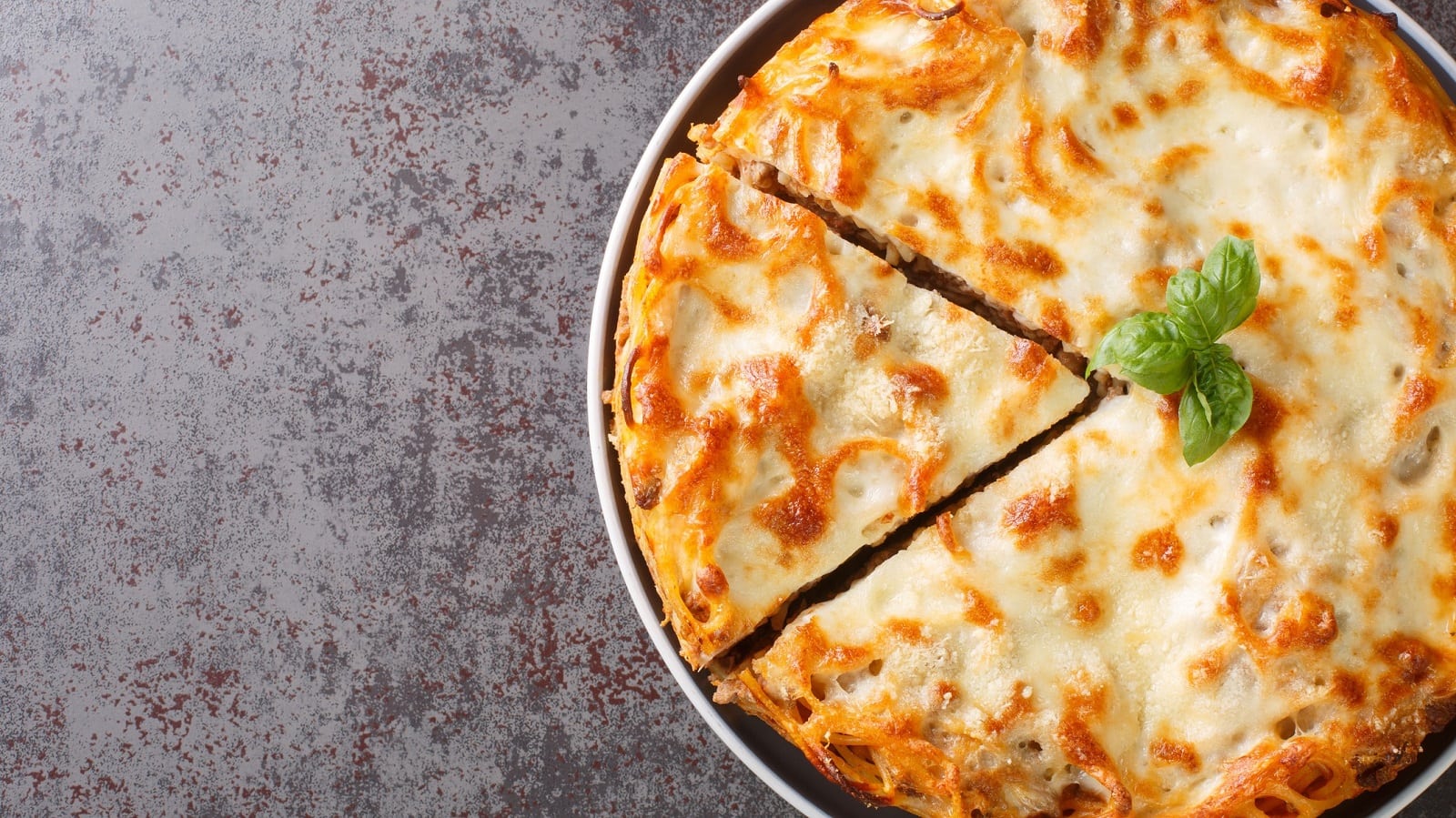 Eine runde Form mit Spaghetti-Kuchen auf grauem Hintergrund.