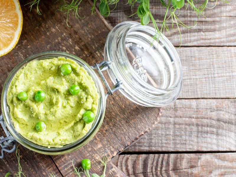 Ein Glas mit Erbsen-Guacamole auf Holzhintergrund