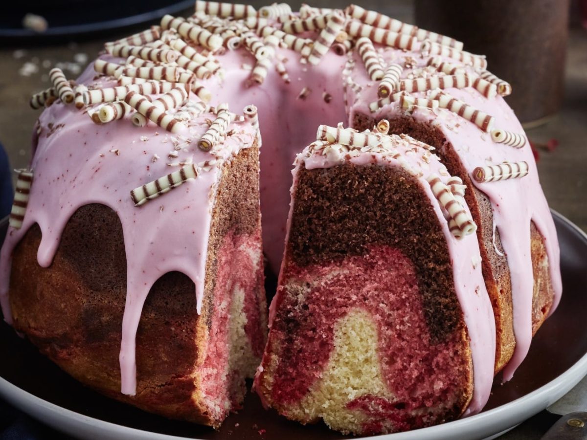 Fürst-Pückler-Gugelhupf auf einem Tortenteller garniert mit rosa Guss und Zebraröllchen.