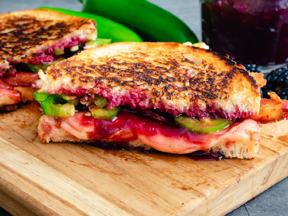 Grilled Cheese mit Jalapeño und Brombeeren auf einem Holzbrett.