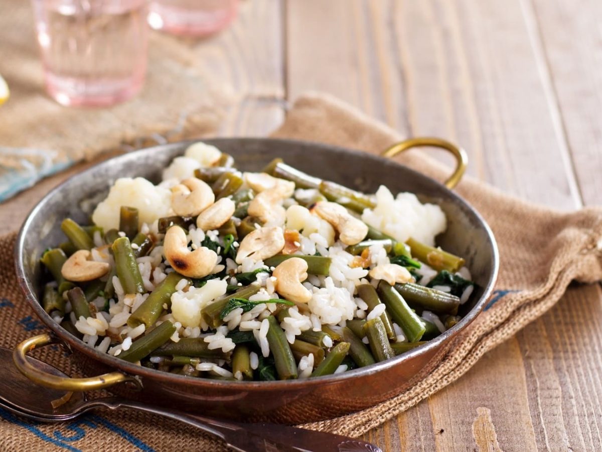 Eine kleine Pfanne grüne Bohnen mit Reis und Cashews.