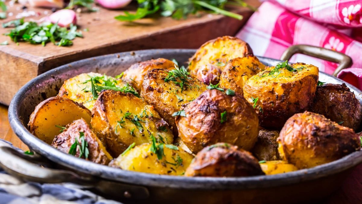 Eine Auflaufform Melting Potatoes, mit Kräutern bestreute gebackene Kartoffelstücke.