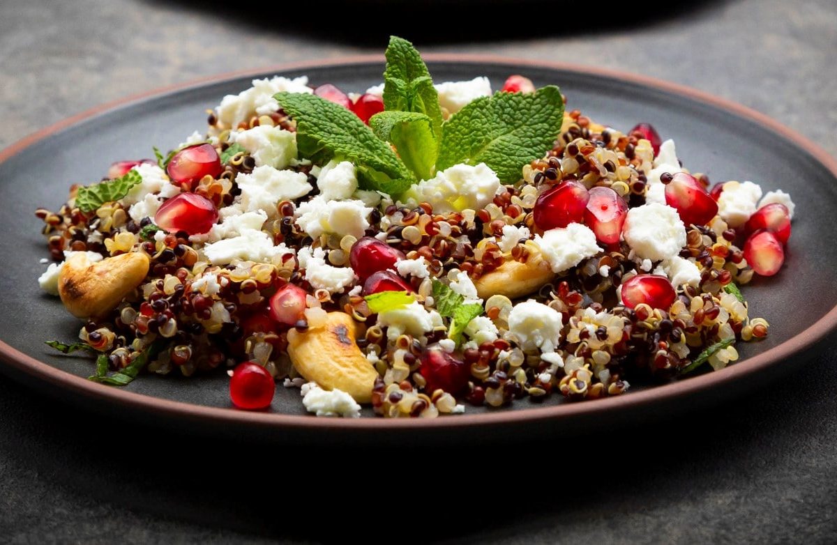 Ein schwarzer Teller mit dem Quinoa auf einem dunkelgrauen Untergrund.