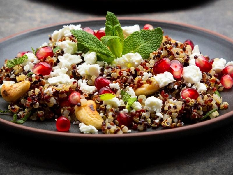 Ein schwarzer Teller mit dem Quinoa auf einem dunkelgrauen Untergrund.