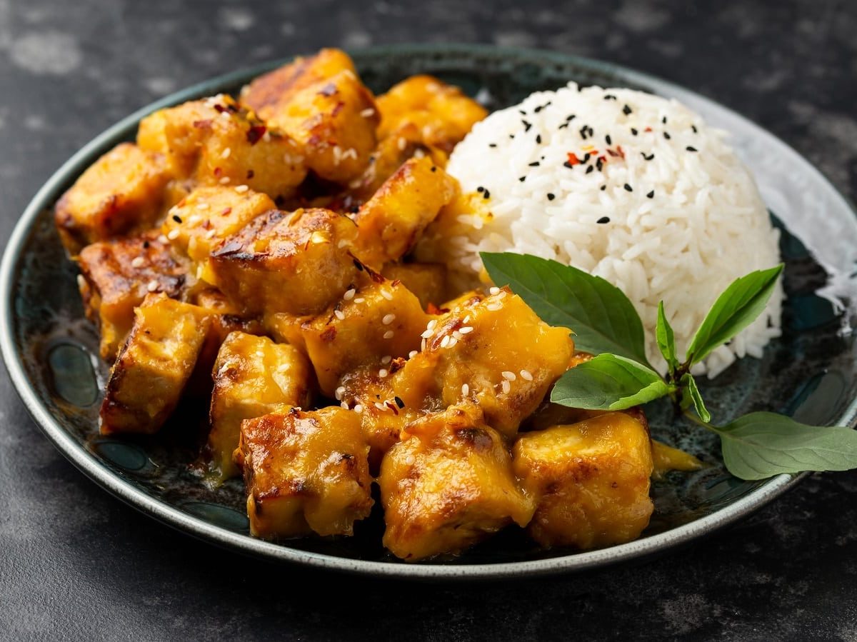 Ein dunkler Teller mit Reis und Sticky Mango Tofu