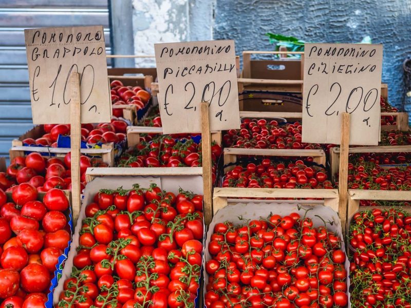 Frontalsicht: Ein marktstand mit vielen verschiedenen TOmaen-sorten, die in Holzkisten angeboten werden