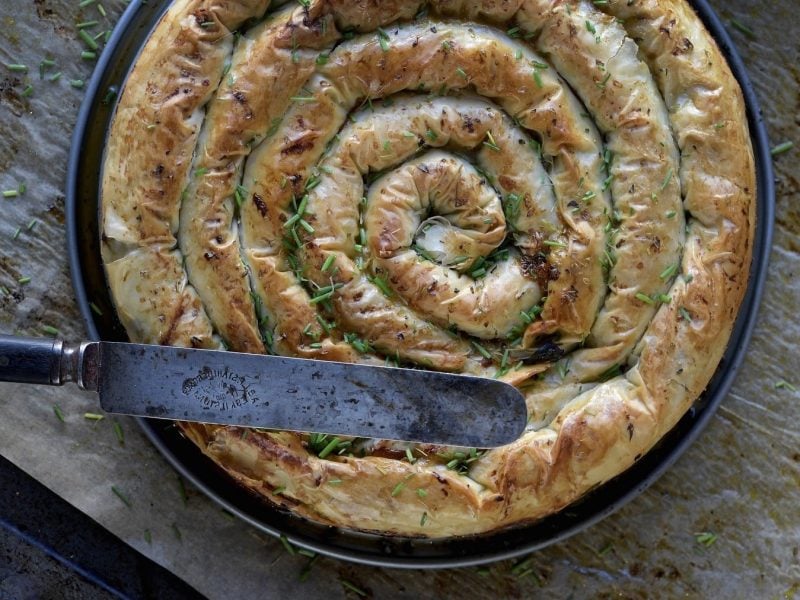 Börek mit Kürbis, Spinat und Feta, zu einer Schnecke aufgerollt serviert in einer gusseisernen Pfanne und garniert mit frischem Schnittlauch.