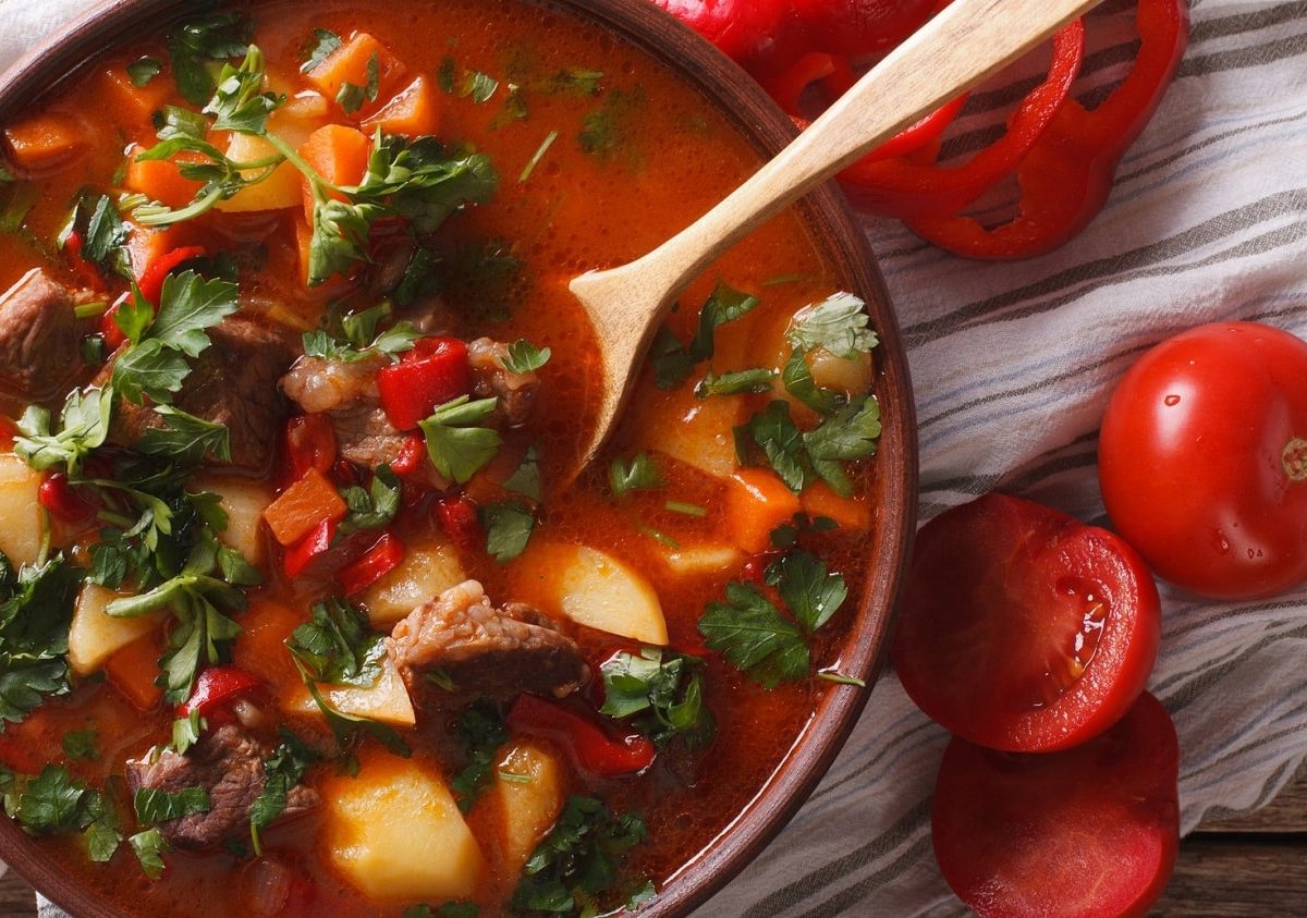 Gulaschsuppe mit Fleisch, Kartoffeln und Gemüse in brauner Schüssel.