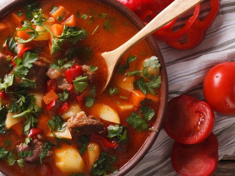 Gulaschsuppe mit Fleisch, Kartoffeln und Gemüse in brauner Schüssel.