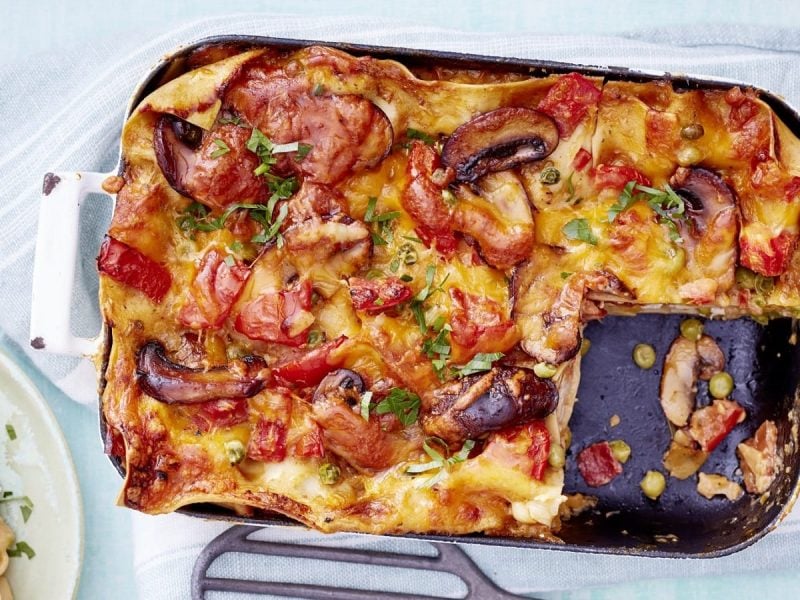 In einer Auflauf-Form ist eine Hähnchen-Lasagne angerichtet. Sie ist mit Pertersilie bestreut und mit Käse überbacken.