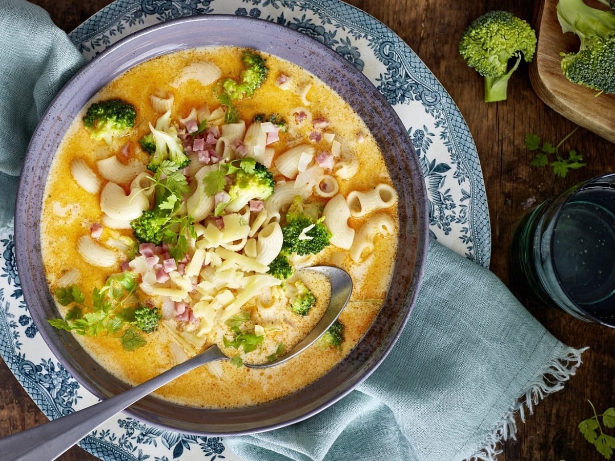 In einer Schüssel ist eine Mac-and-Cheese-Suppe angerichtet. Sie ist mit Kerbel garniert.