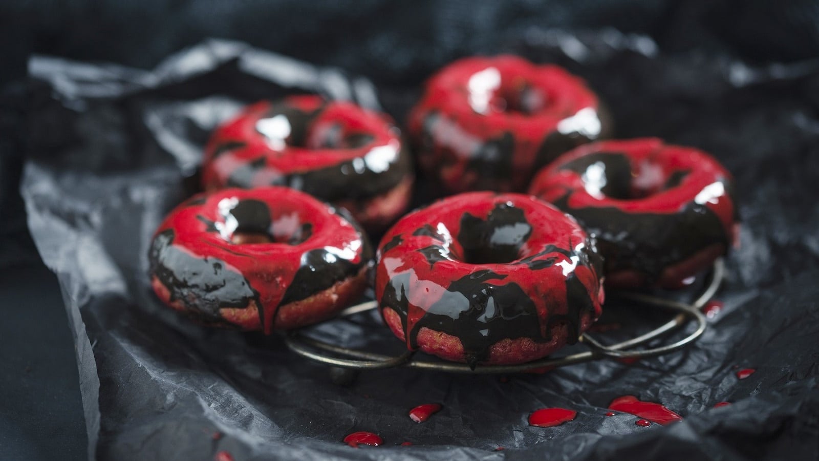 Auf einem schwarzen Teller liegen Rote-Bete-Donuts mit Schokoladenglasur. Sie sind mit roter und schwarzer Glasur überzogen.