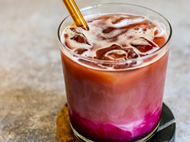 Rote-Bete-Latte mit Eiswürfeln in einem Drink-Glas auf Marmortisch.