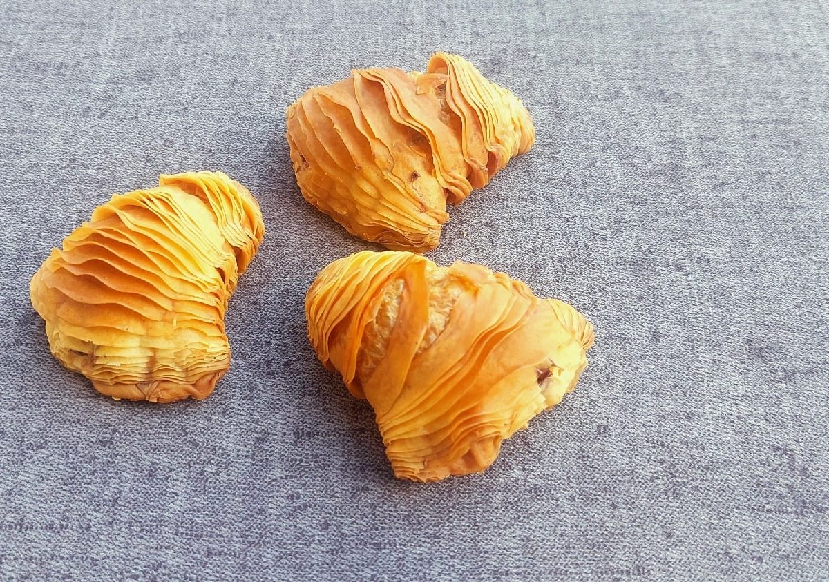 Drei Sfogliatelle auf einem grauen Untergrund.