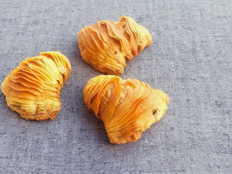 Drei Sfogliatelle auf einem grauen Untergrund.