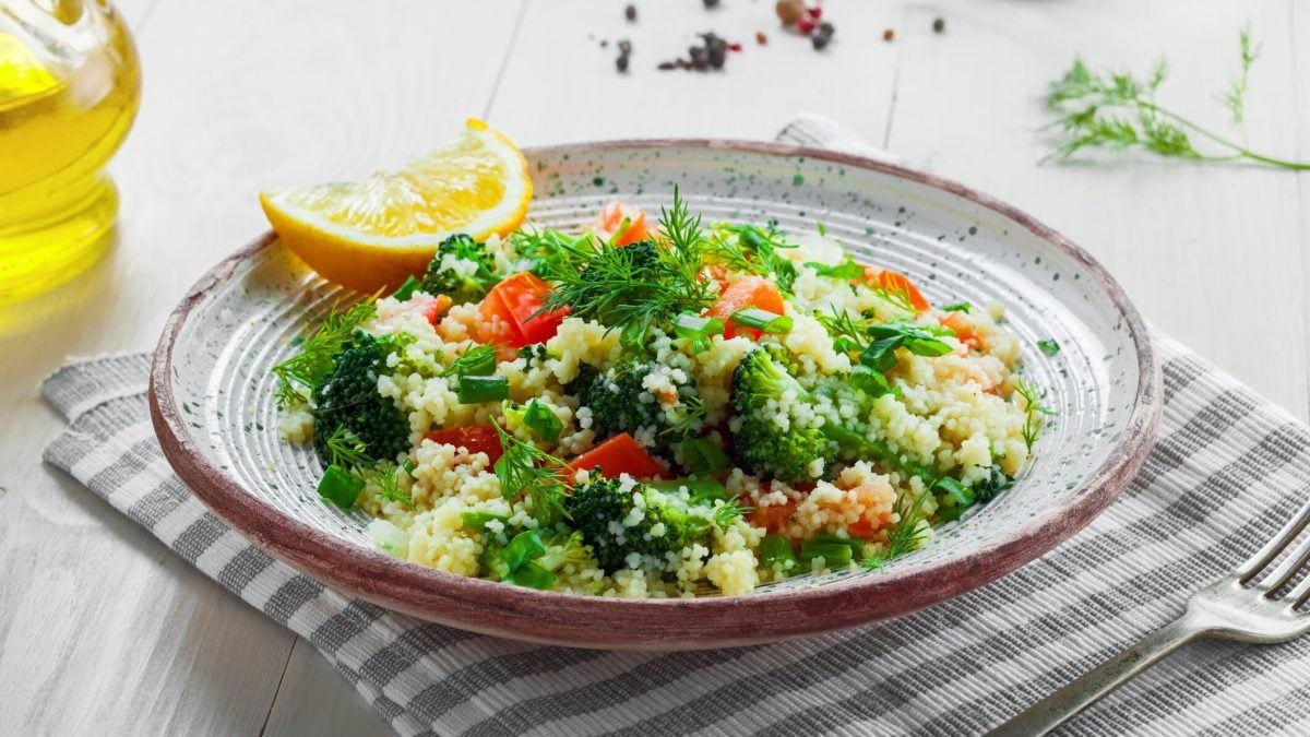 Ein Teller Brokkoli-Couscous-Salat mit frischen Kräutern und Tomaten.