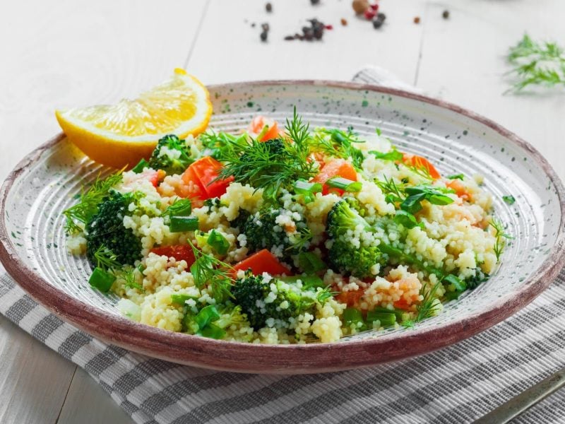 Ein Teller Brokkoli-Couscous-Salat mit frischen Kräutern und Tomaten.