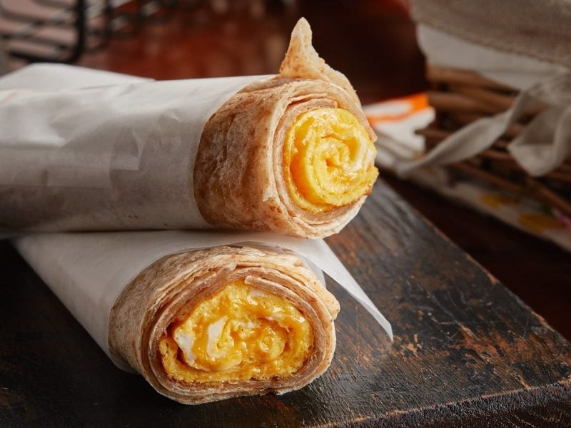 Zwei Chapati Egg Rolls auf einem Holzbrett.