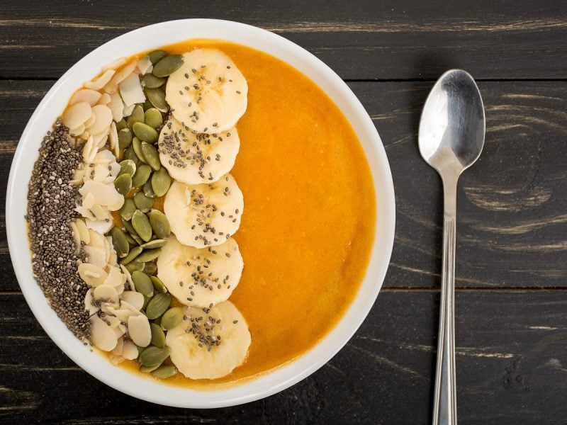 Eine Kürbis-Smoothie-Bowl auf einem dunklen Holztisch.