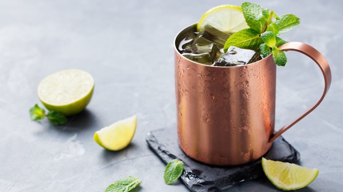 Ein Kupferbecher mit Mexican Mule neben frischen Limetten.