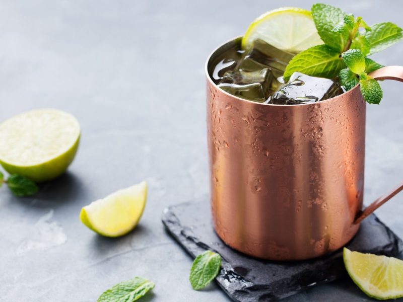 Ein Kupferbecher mit Mexican Mule neben frischen Limetten.