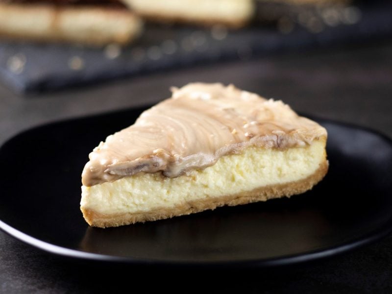 Ein schwarzer Teller mit einem Stück White Chocolate Cheesecake