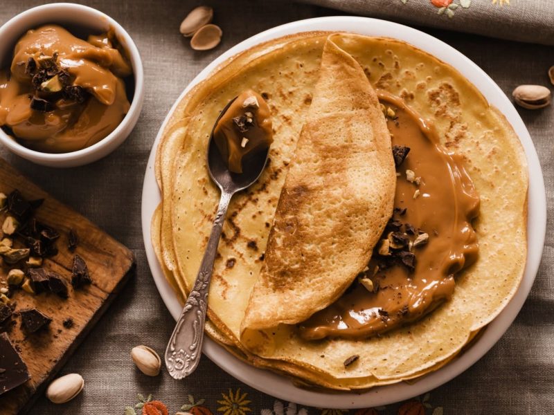 Eierkuchen mit selbstgemachtem Dulce de Leche auf einem Teller, garniert mit Schokolade und Nüssen.