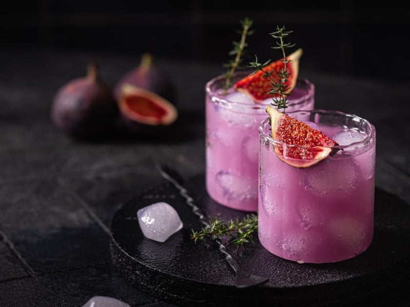 Zwei Gläser mit der violetten Limonade auf einem schwarzen Tisch.