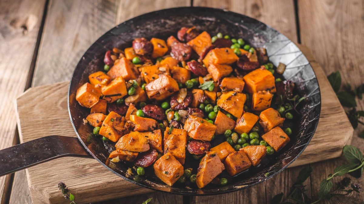 Kürbis-Erbsen-Pfanne mit veganer Chorizo auf einem Holzbrett.