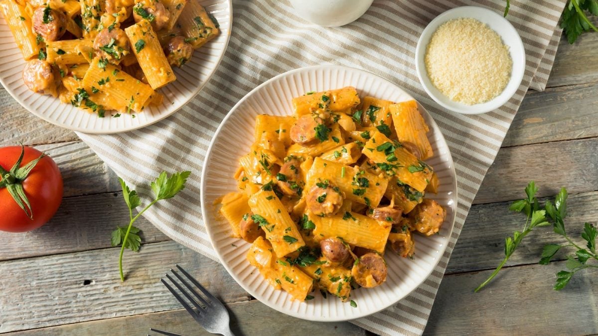 Zwei Teller mit Rigatoni mit Fenchel und Wurst auf einem Küchentuch