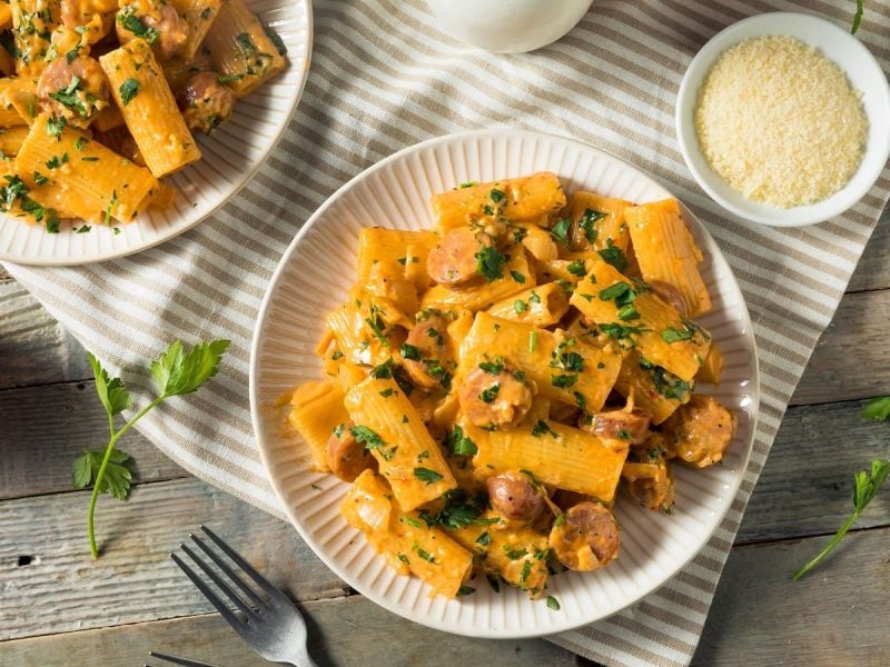 Zwei Teller mit Rigatoni mit Fenchel und Wurst auf einem Küchentuch