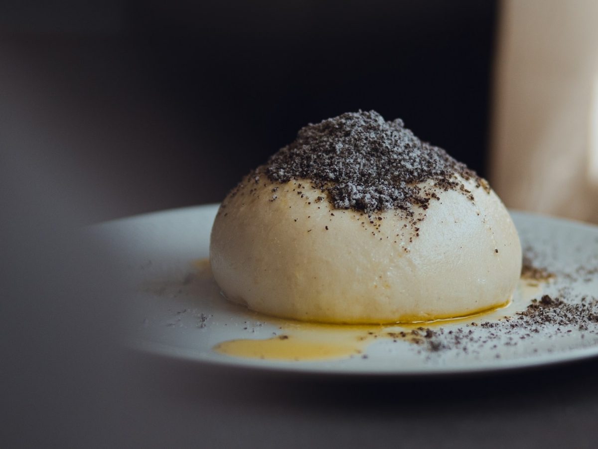 Ein veganer Germknödel mit Mohn und zerlassener Margarine auf einem Teller.