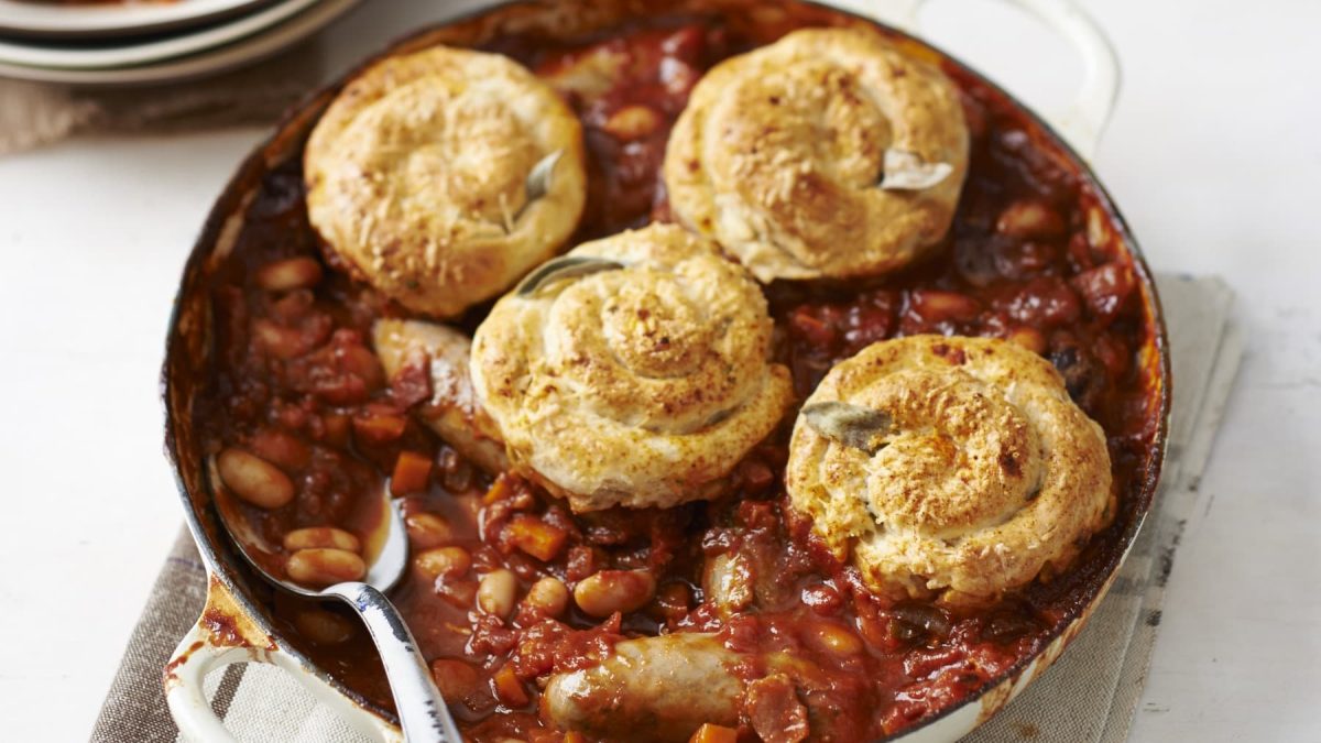 Wurst-Parmesan-Cobbler in einer Ofenform mit Löffel drin vor hellem Hintergrund.