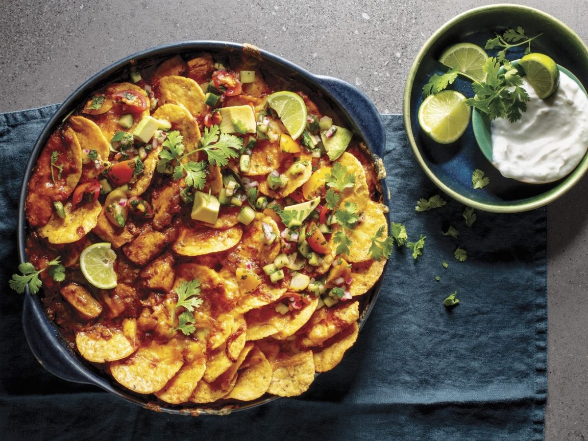 Hühnchen-Nachos mit Kokos-Dip, frischem Koriander und Limette, serviert auf einem blauen Küchentuch.