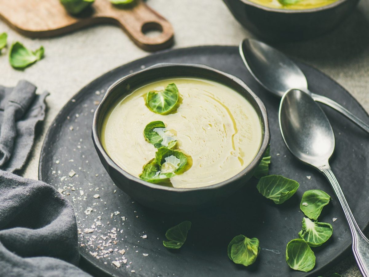 Rosenkohlsuppe in schwarzer Schüssel auf schwarzem Teller.