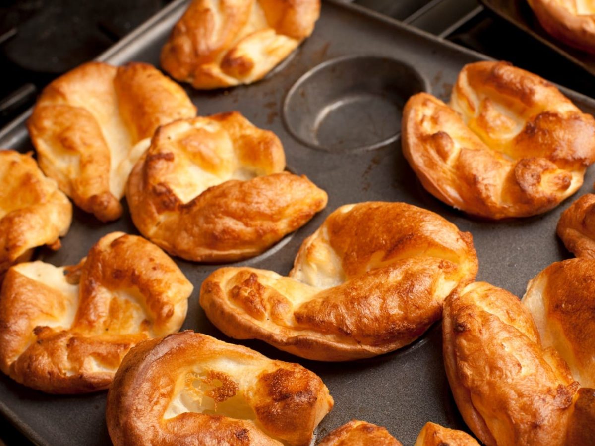 Yorkshire Pudding in einer Muffinform vor schwarzem Hintergrund.