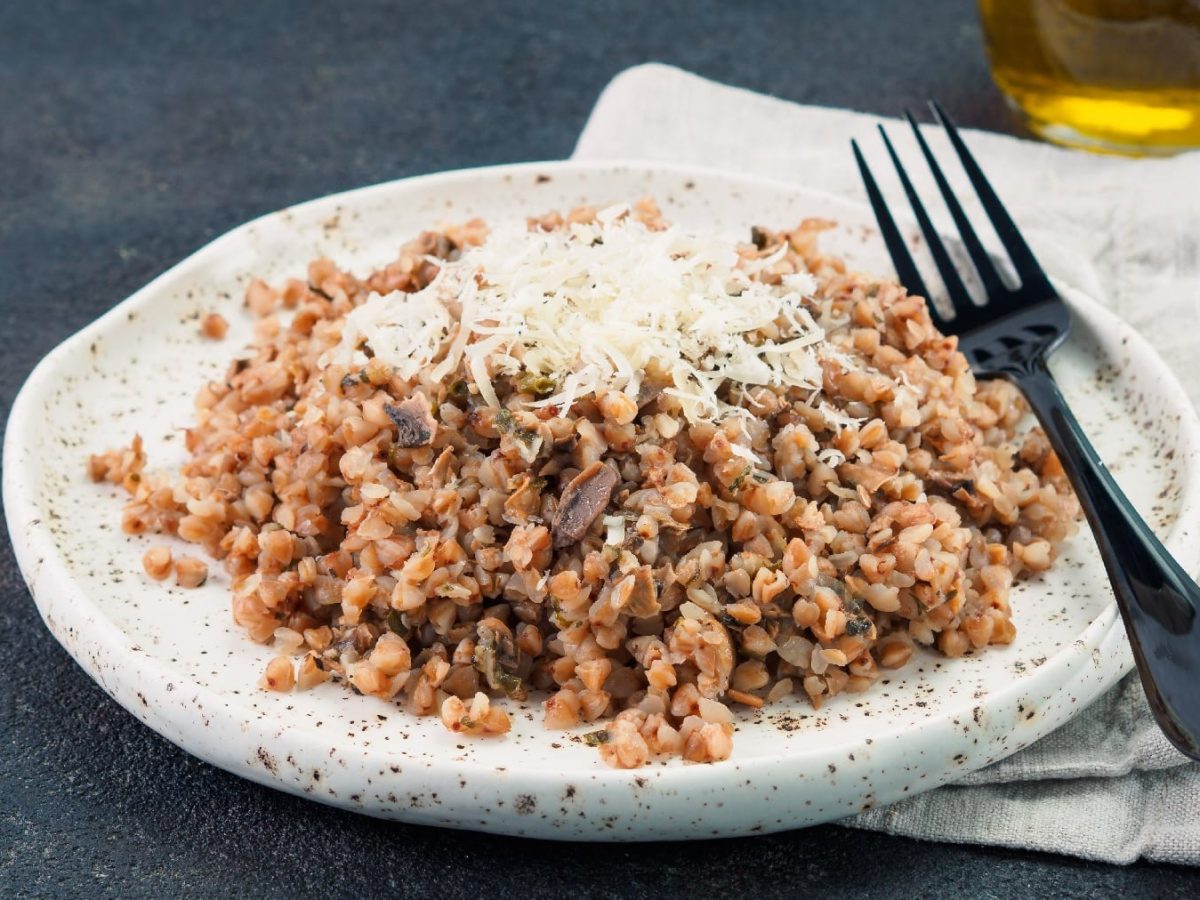 Ein weißer, dicker Teller mit dem Buchweizenrisotto und Käse.