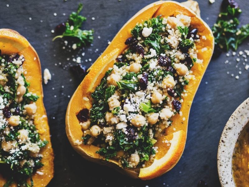 Gefüllter Butternut mit Grünkohl, Quinoa und Cranberrys auf einer dunklen Schieferplatte.