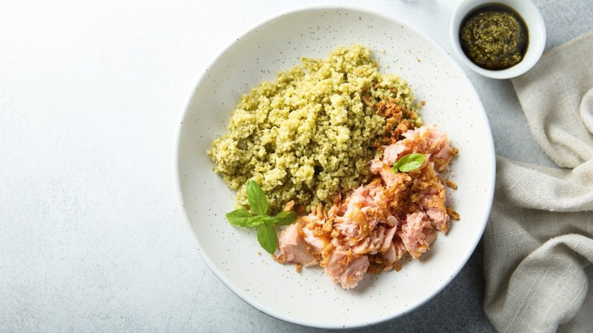 Ein weißer runder Teller mit Knusper-Lachs mit Pesto-Couscous.